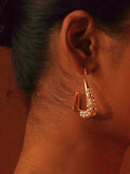 Close profile of Maré natural pearl statement earring in 24k gold worn on model in warm editorial light.