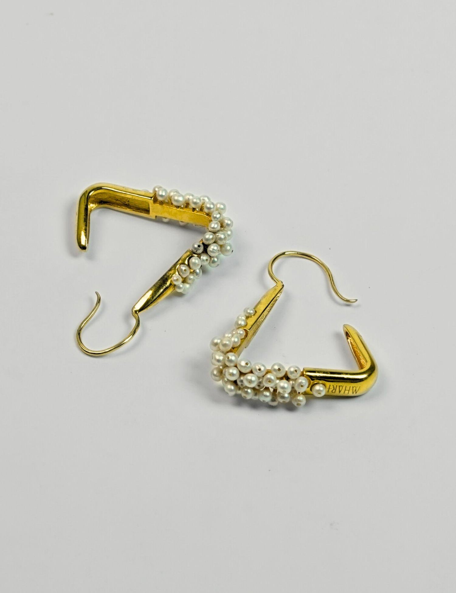 Maré Pearl Hanger earrings with natural pearl beads on triangular gold form in 24k gold on neutral background.