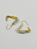 Maré Pearl Hanger earrings with natural pearl beads on triangular gold form in 24k gold on neutral background.