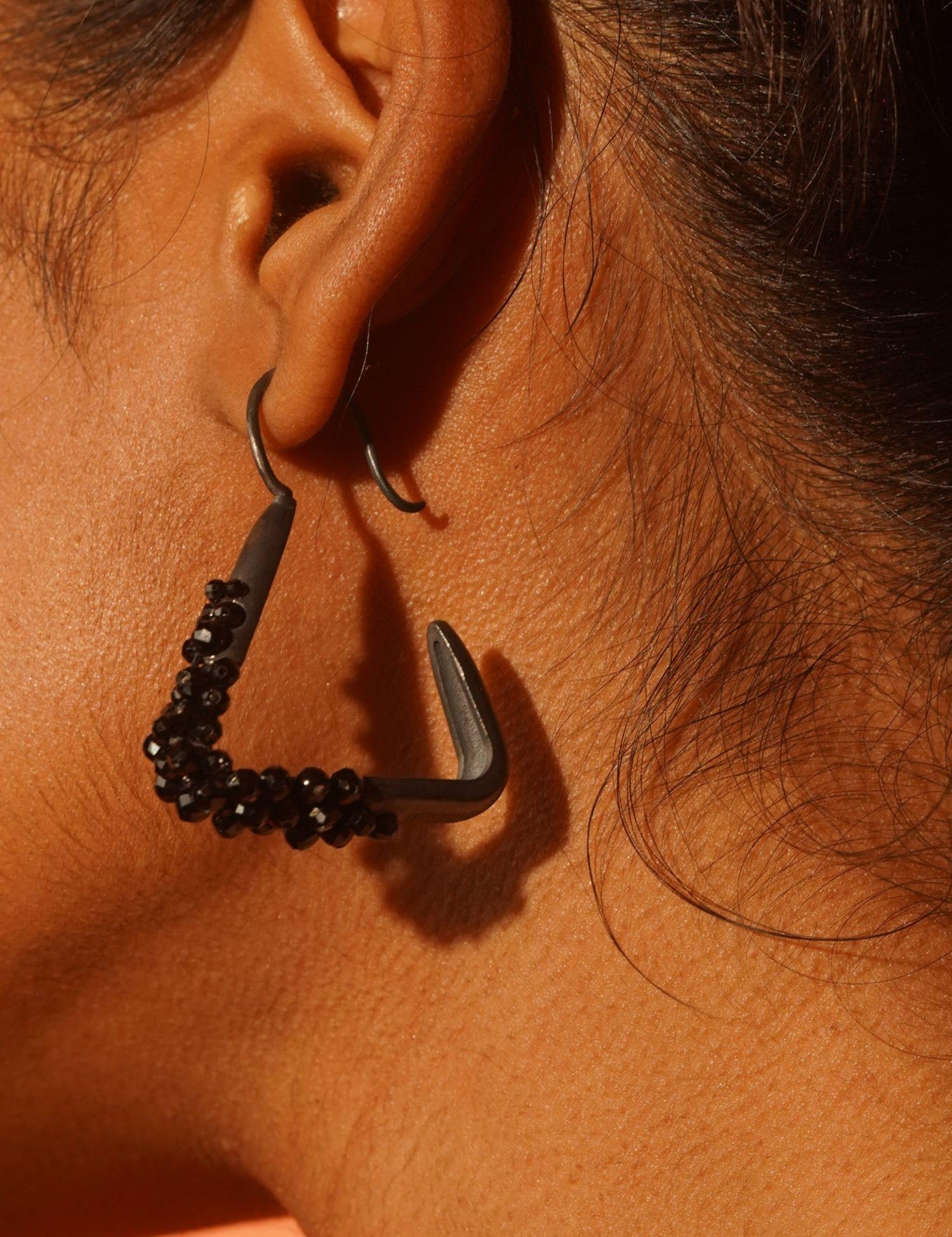 Maré black rhodium hanger earring with natural spinel cluster worn in profile close-up on model.