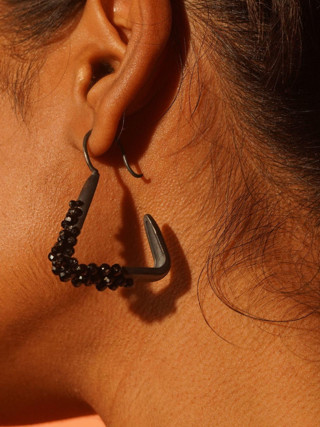 Maré Pearl Hanger earrings with natural pearl beads on triangular gold form in 24k gold on neutral background.