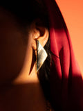 Mosaic mother of pearl drop earrings in dramatic warm editorial lighting against a red backdrop.