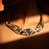 Mosaic mother of pearl statement necklace worn on the collarbone in warm directional light.