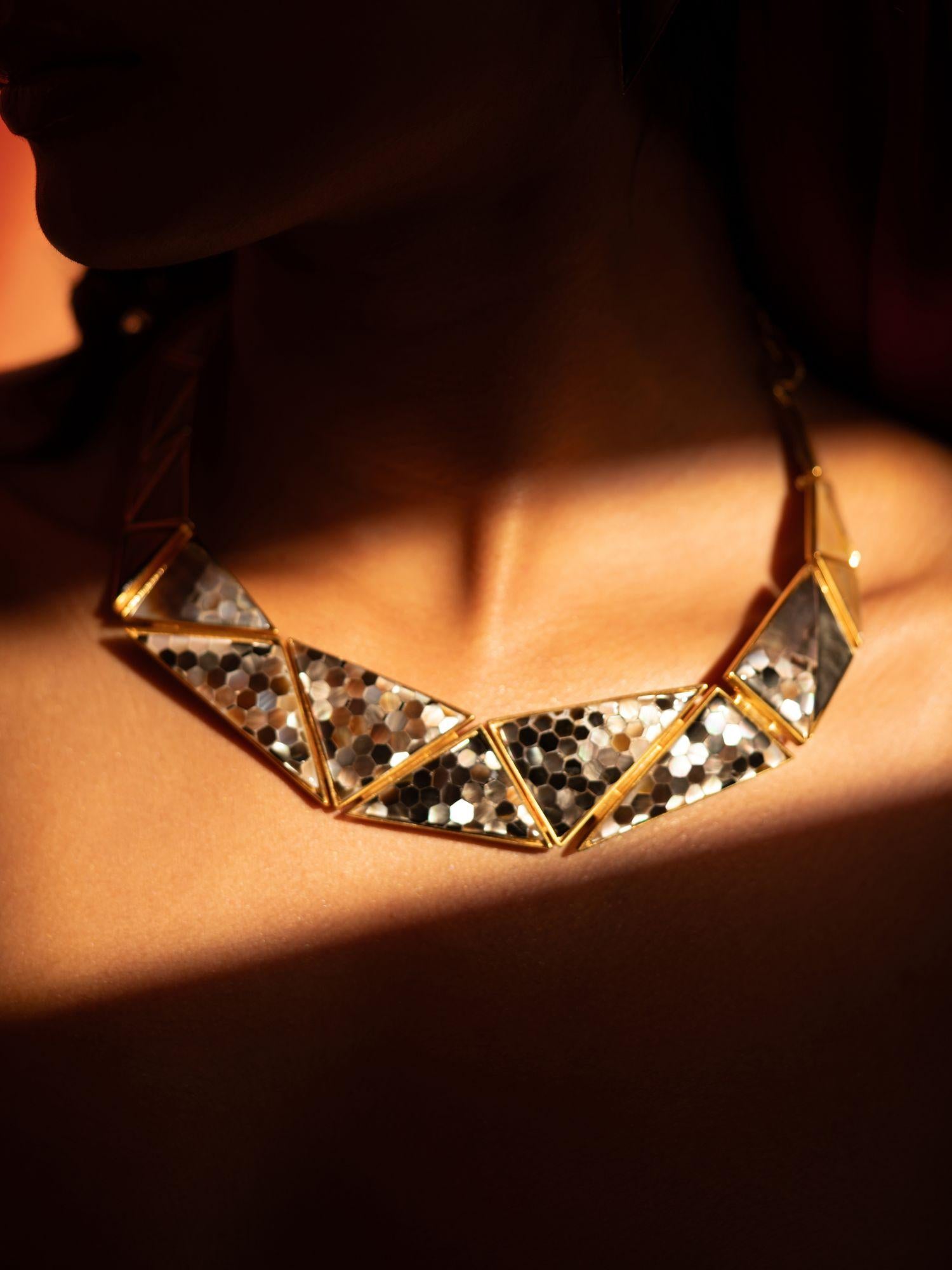 Mosaic mother of pearl statement necklace worn on the collarbone in warm directional light.