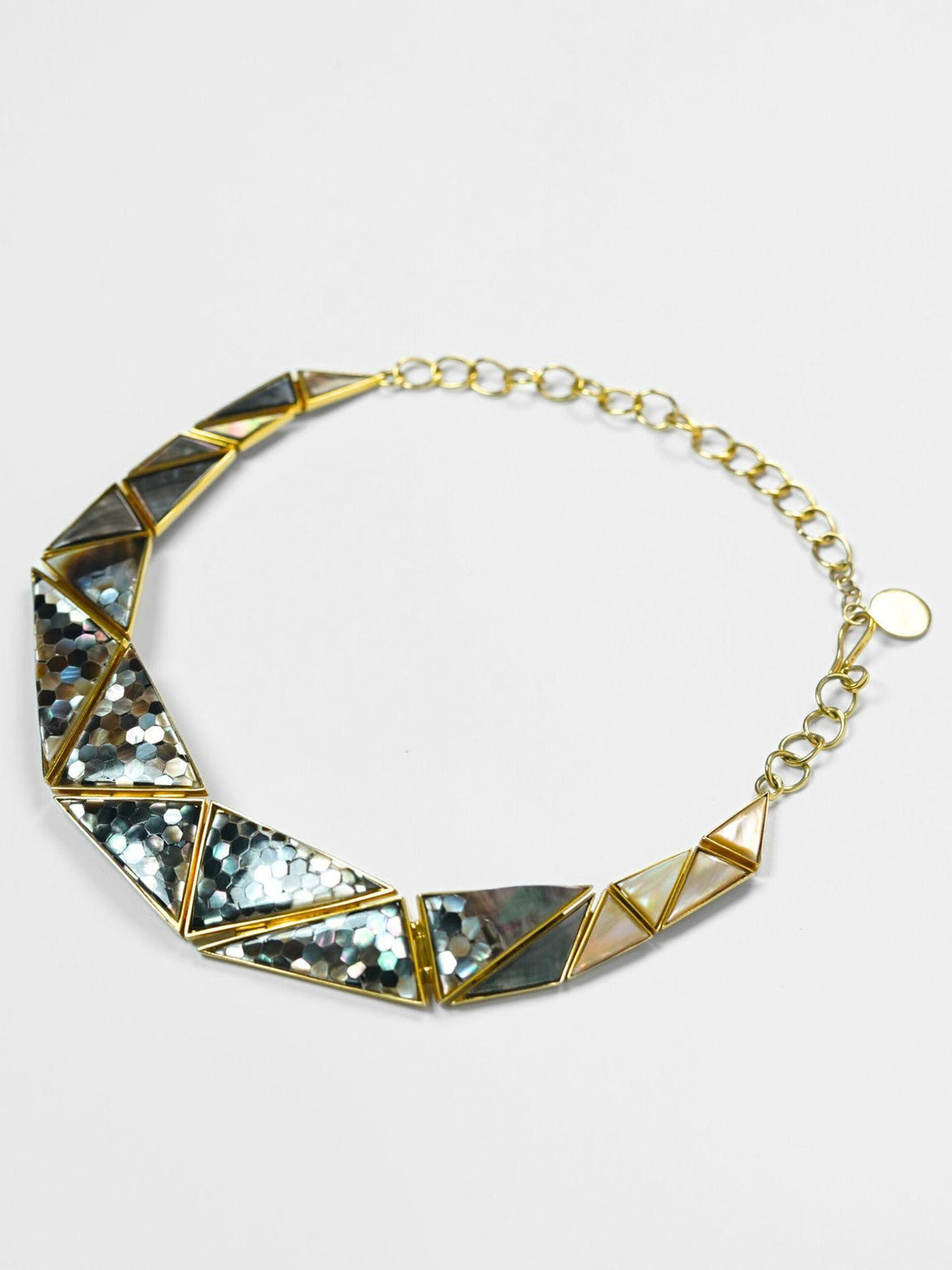 Mosaic mother of pearl statement necklace worn on the collarbone in warm directional light.