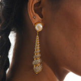 Close profile of Neris pearl and gold shell drop earring worn on model against clean background.