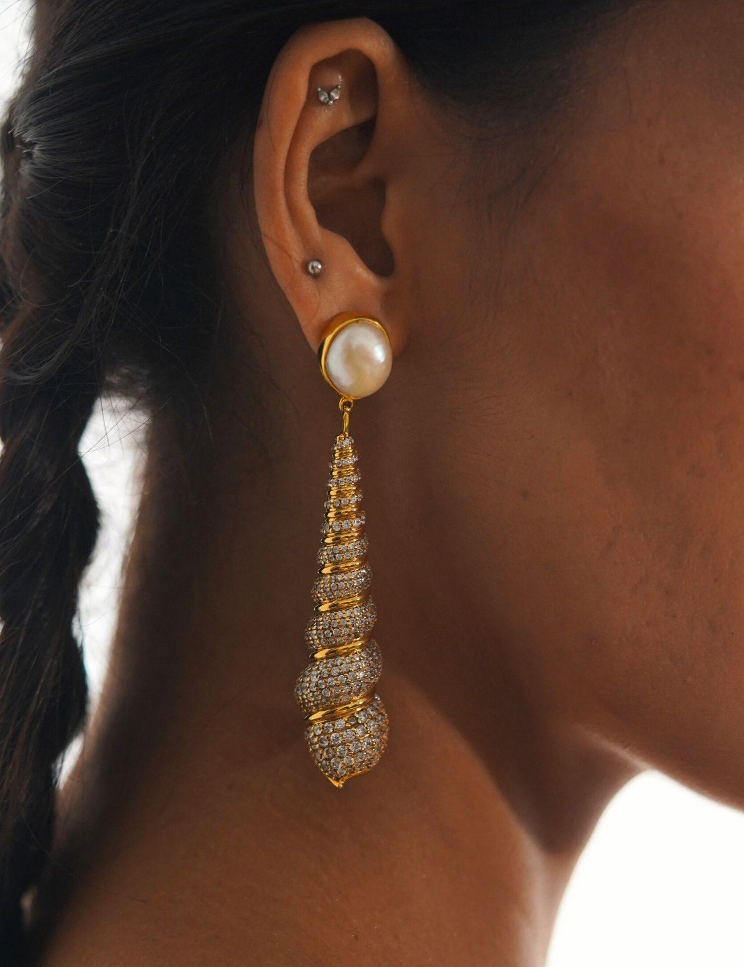 Close profile of Neris pearl and gold shell drop earring worn on model against clean background.