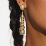 Neris gold shell drop statement earrings worn in profile showing full length against braided hair.