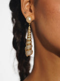 Neris gold shell drop statement earrings worn in profile showing full length against braided hair.