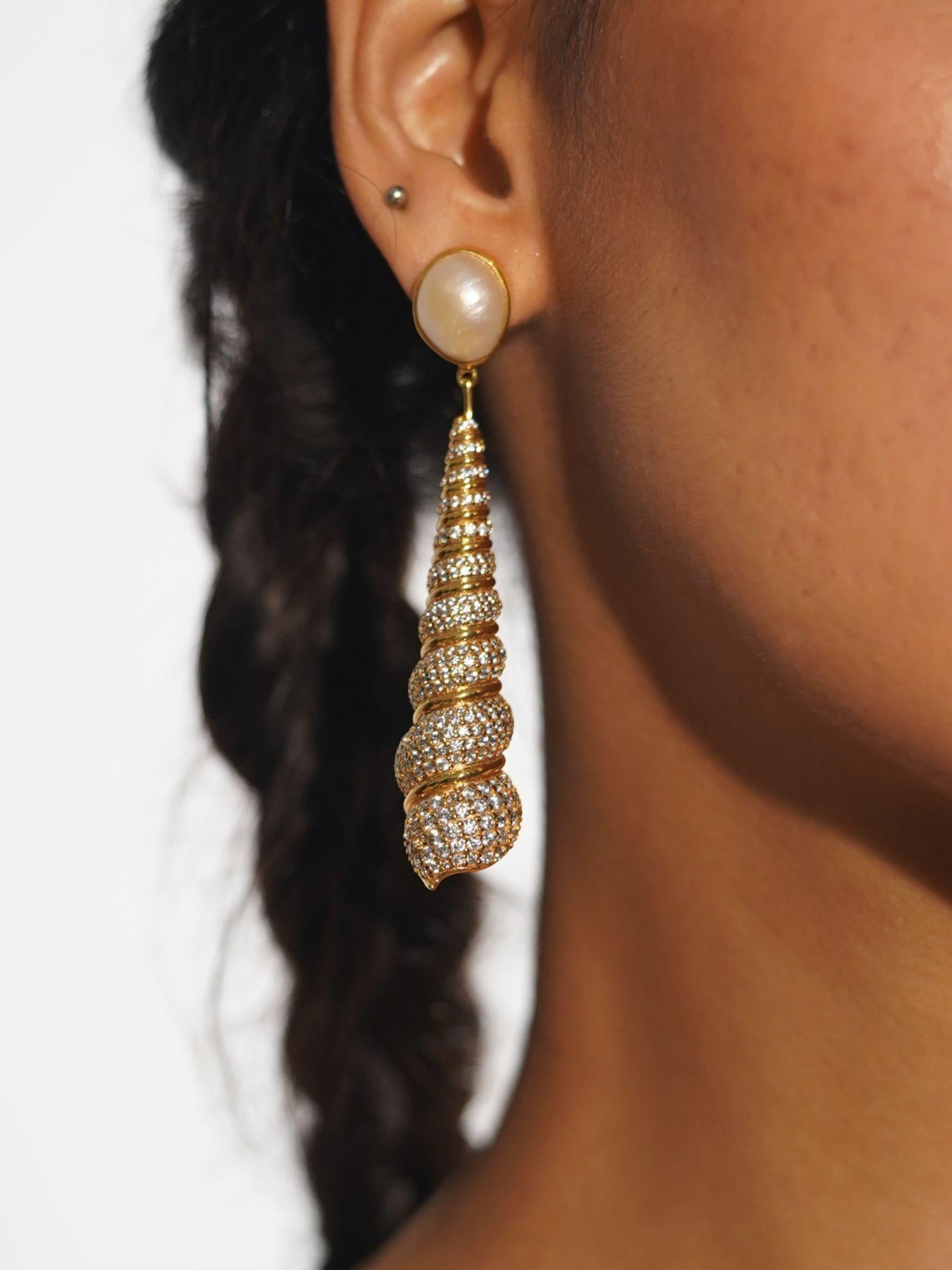 Neris gold shell drop statement earrings worn in profile showing full length against braided hair.