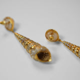 Angled product shot of Neris gold shell drop earrings showing full length and spiral texture detail.