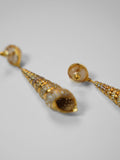 Angled product shot of Neris gold shell drop earrings showing full length and spiral texture detail.