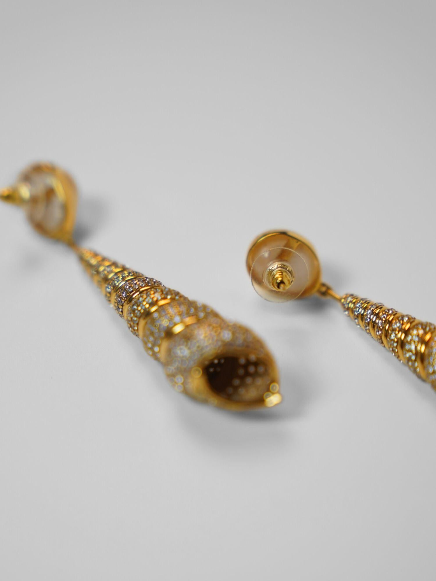 Angled product shot of Neris gold shell drop earrings showing full length and spiral texture detail.