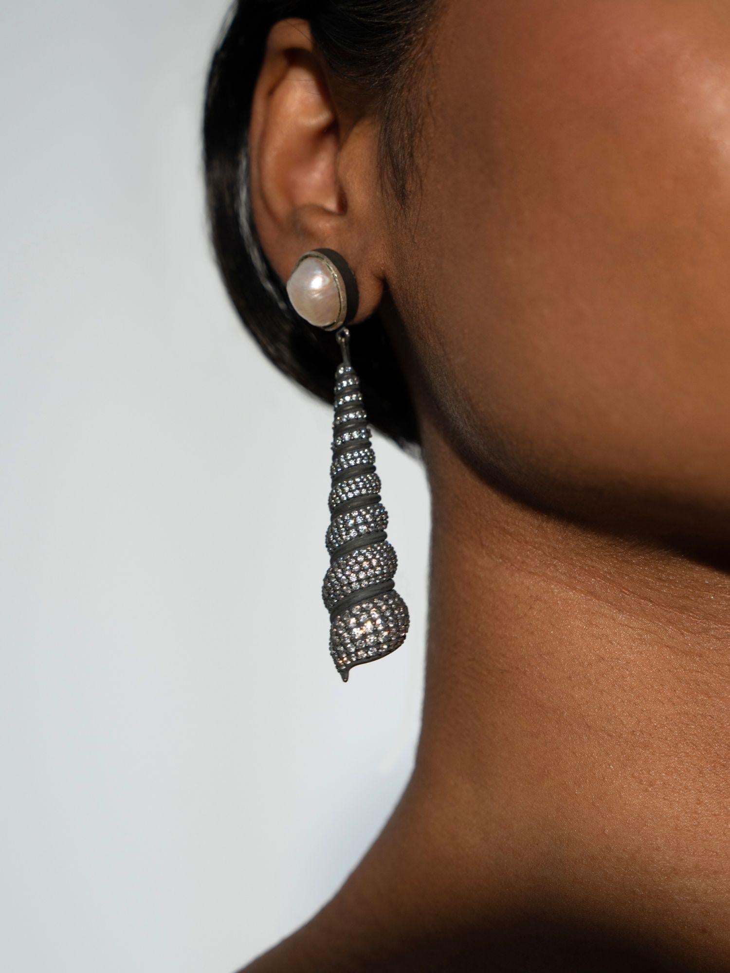 Close profile of Neris pearl and oxidised silver shell drop statement earring on model.