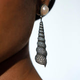 Neris oxidised silver shell drop earring worn in profile showing full spiral length on model.