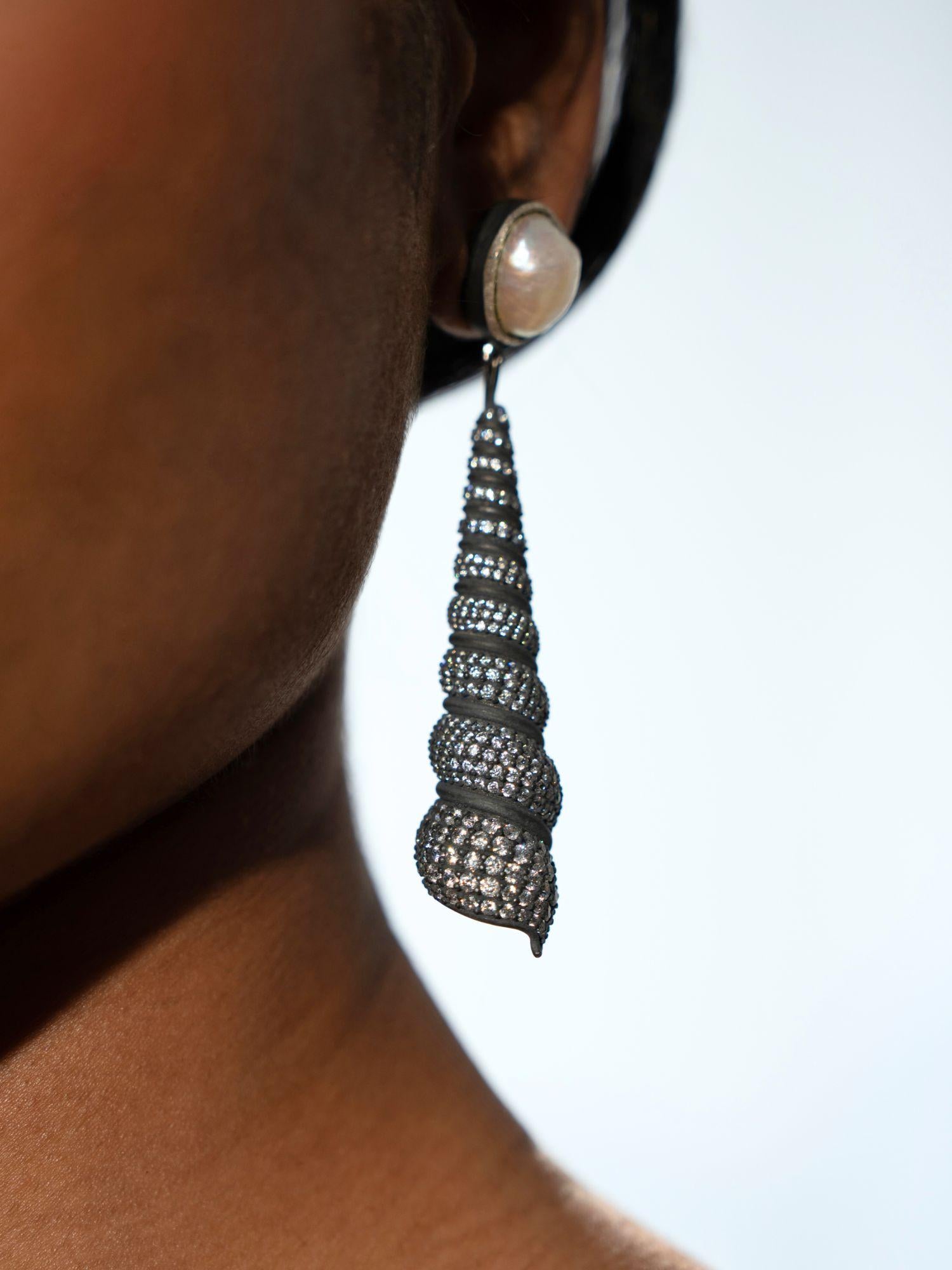 Neris oxidised silver shell drop earring worn in profile showing full spiral length on model.