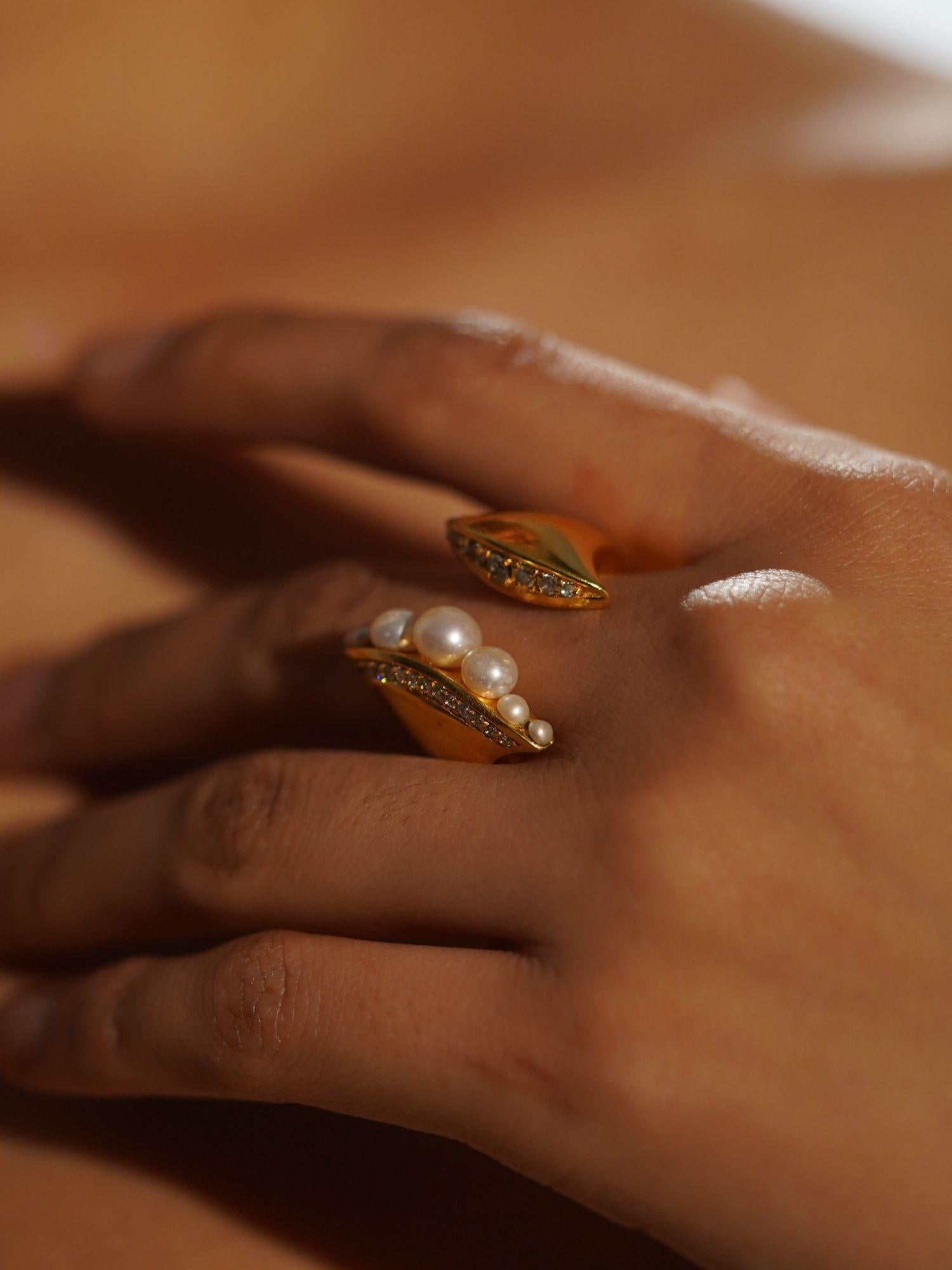 Close-up of Noira natural pearl ring and zircon ring worn together on hand in warm golden light.