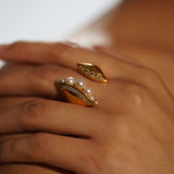 Noira pearl cocktail ring with zircon band on model's hand in warm editorial light.