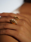 Noira pearl cocktail ring with zircon band on model's hand in warm editorial light.