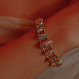 Opal crystal haze statement bracelet worn on wrist in a warm close editorial shot.