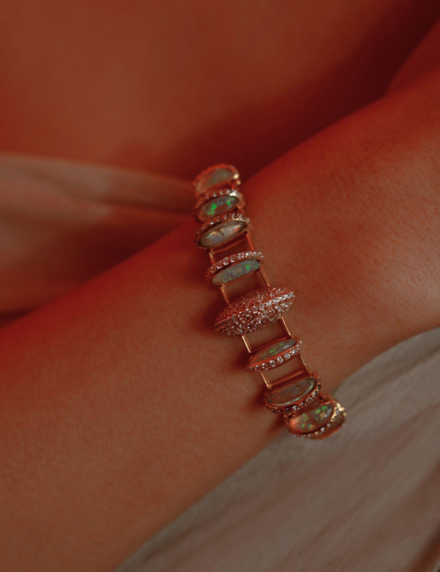 Opal crystal haze statement bracelet worn on wrist in a warm close editorial shot.