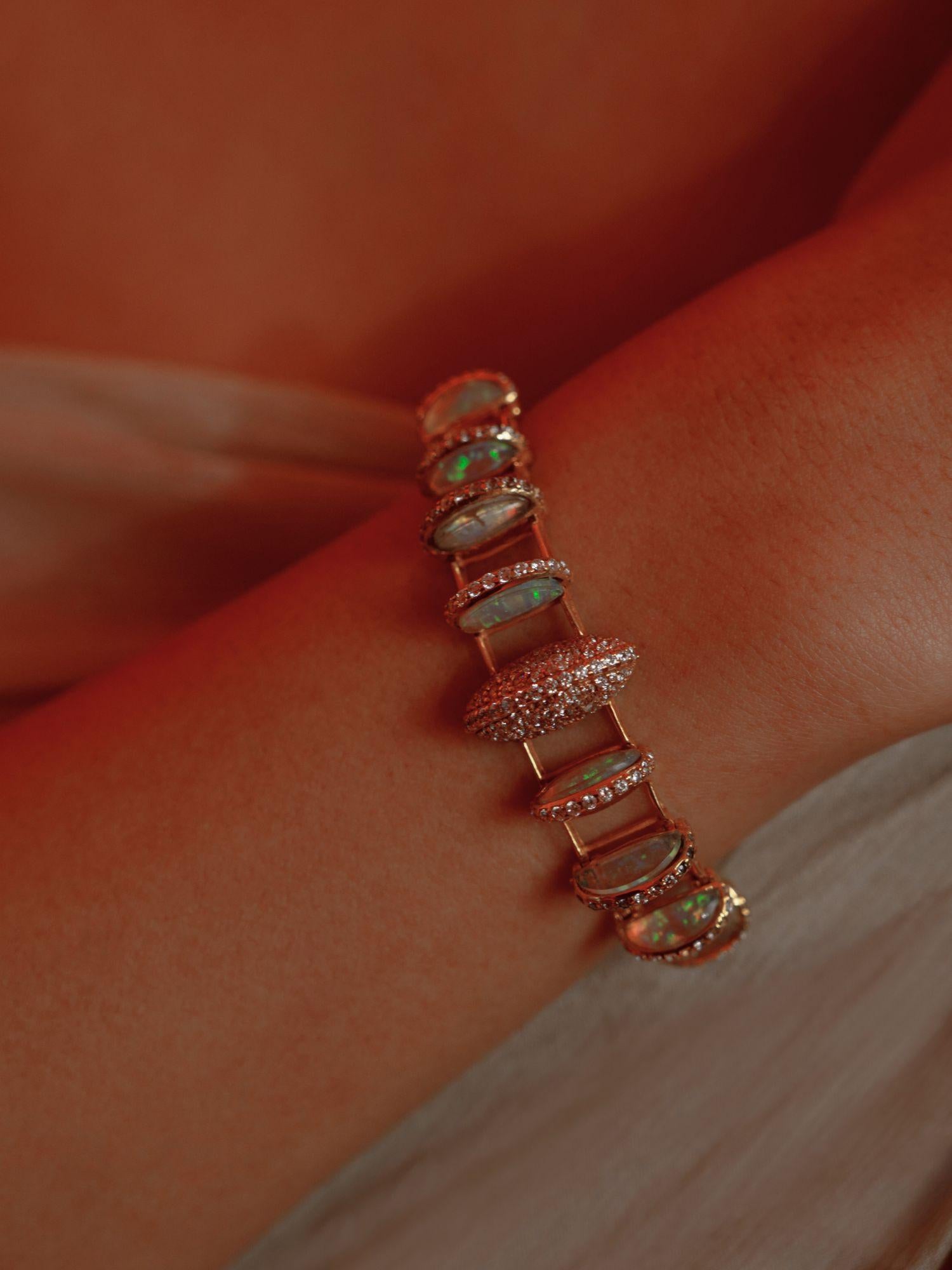 Opal crystal haze statement bracelet worn on wrist in a warm close editorial shot.