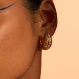 Reversible opal crystal haze hoop earrings worn in profile in warm orange editorial light.