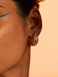 Reversible opal crystal haze hoop earrings worn in profile in warm orange editorial light.