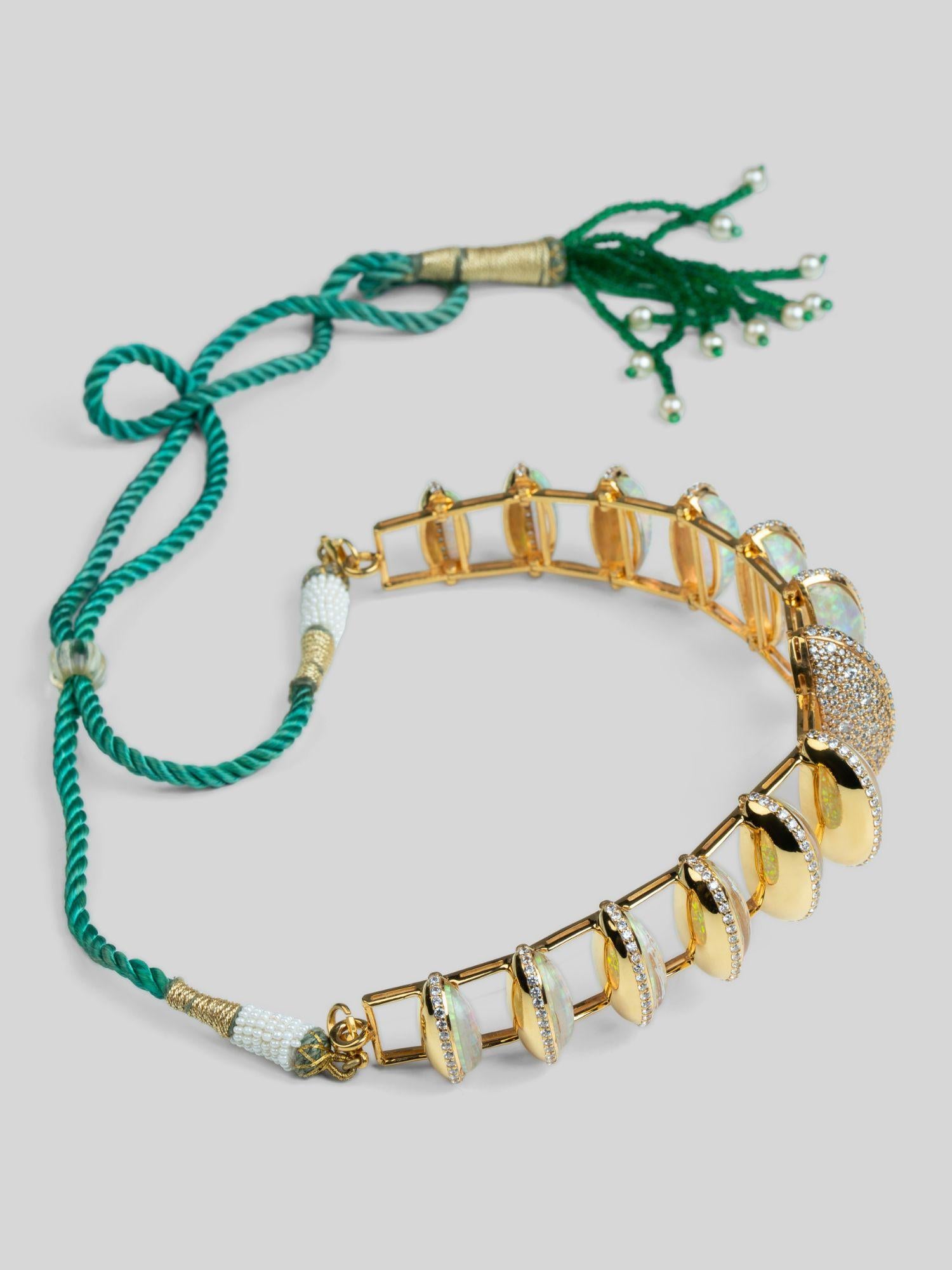 Full flat lay of Opal Perspective opal necklace with green tassel cord and gold stone settings.