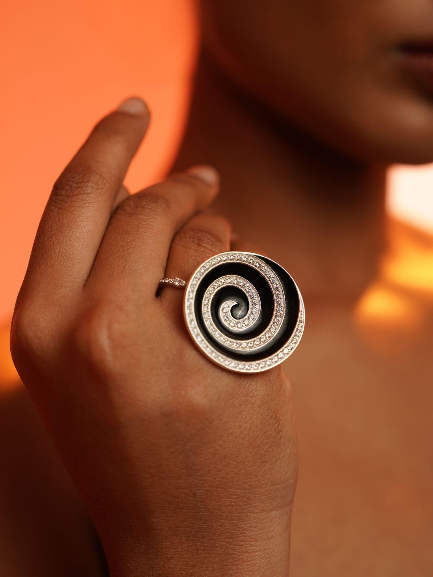 Orbis black enamel cocktail ring in white rhodium worn on hand in dramatic warm editorial light.