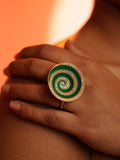 Orbis green enamel cocktail ring worn on hand resting on shoulder in warm orange editorial light.