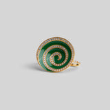 Three-quarter product shot of Orbis green enamel spiral ring in 24k gold on neutral background.
