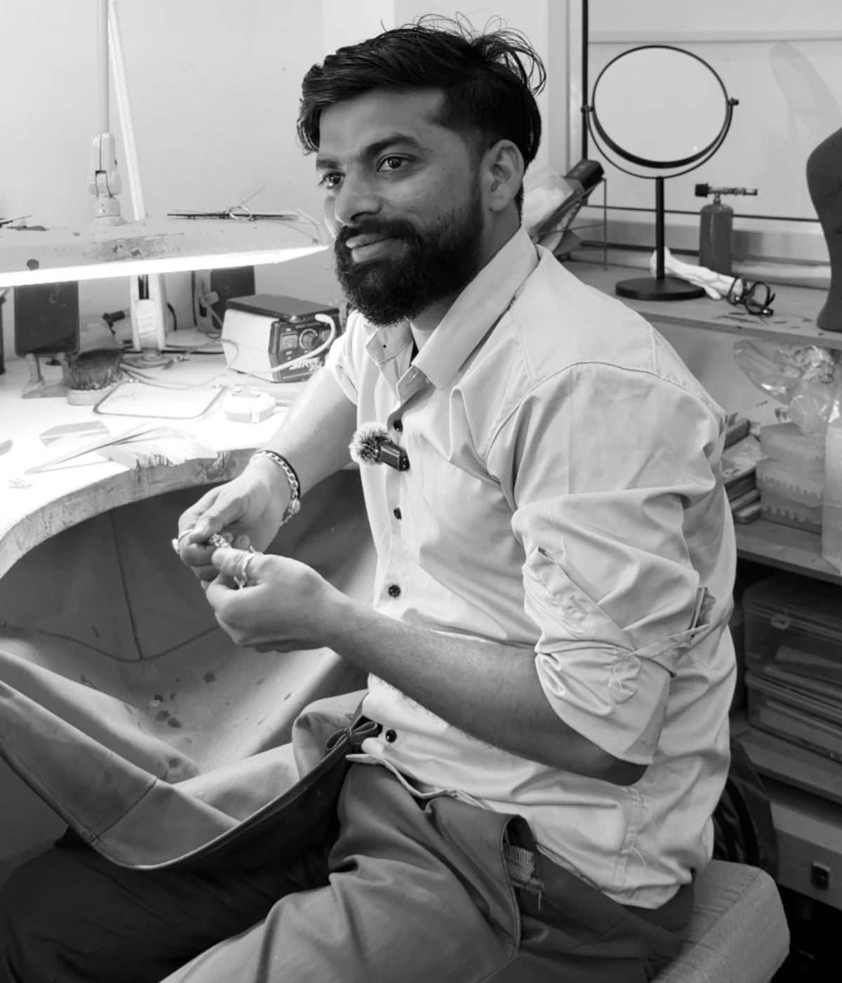 Artisan working in the jewellery studio, seated at workbench, black and white