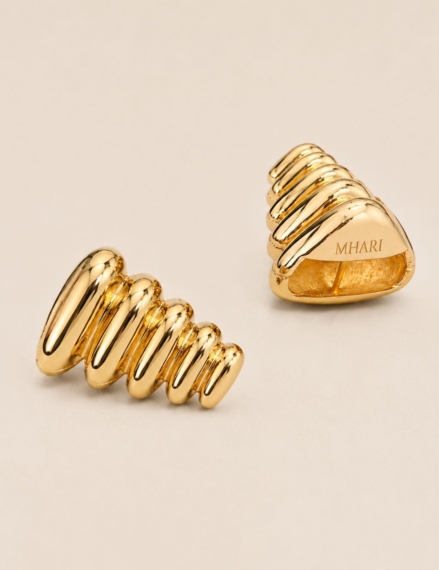 Pebble Triangle earrings in 24k gold showing 3D geometric form and MHARI engraving, magnetic closure visible.