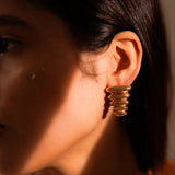 Close-up of gold ribbed triangle pebble earring on model's ear