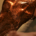 Close-up of hand-hammered copper corset surface showing texture and CZ stone detail