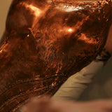 Close-up of hand-hammered copper corset surface showing texture and CZ stone detail