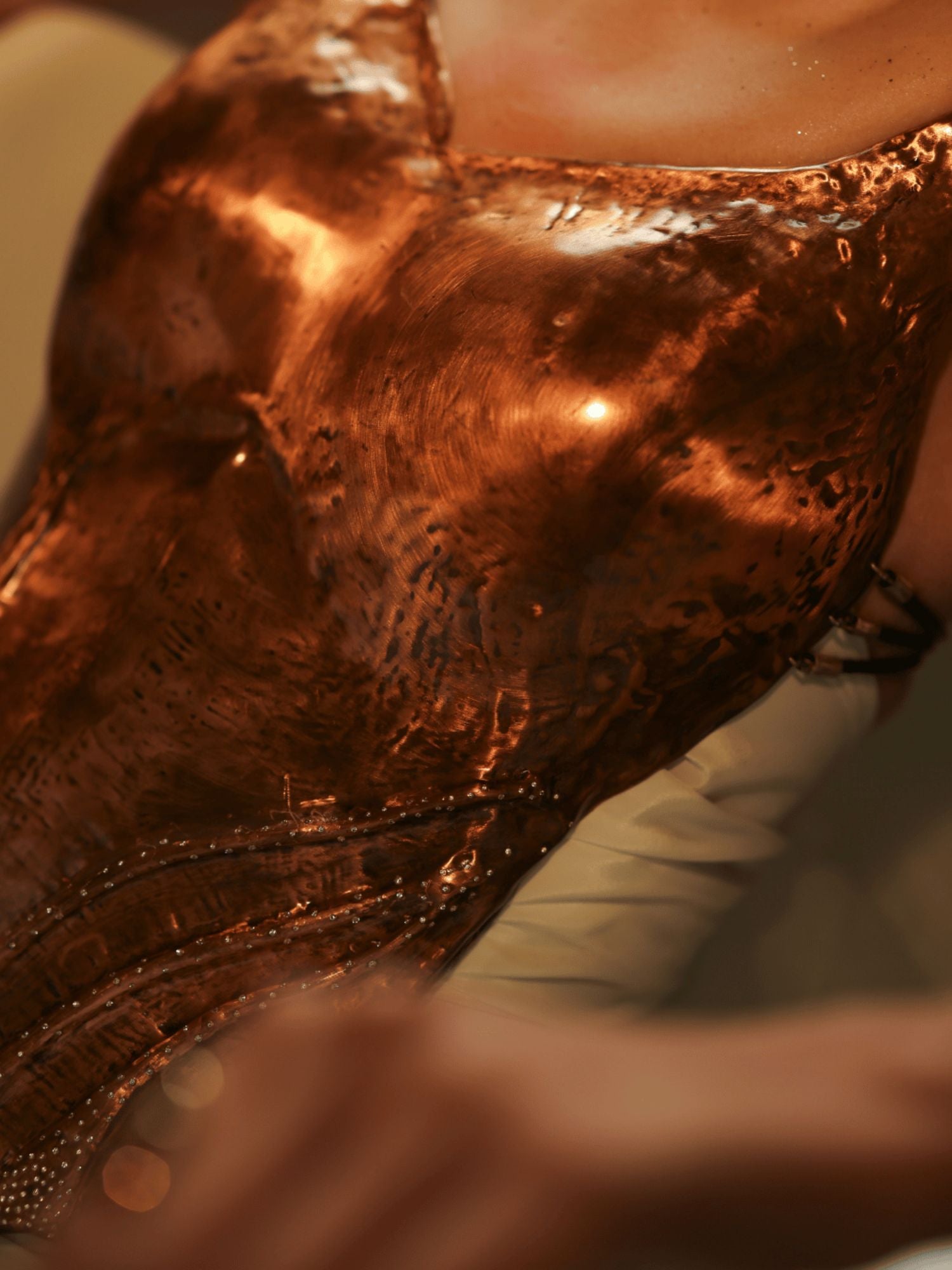 Close-up of hand-hammered copper corset surface showing texture and CZ stone detail