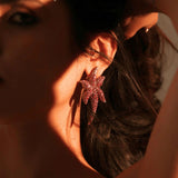 Model wearing sculptural CZ starfish earrings in warm dramatic lighting