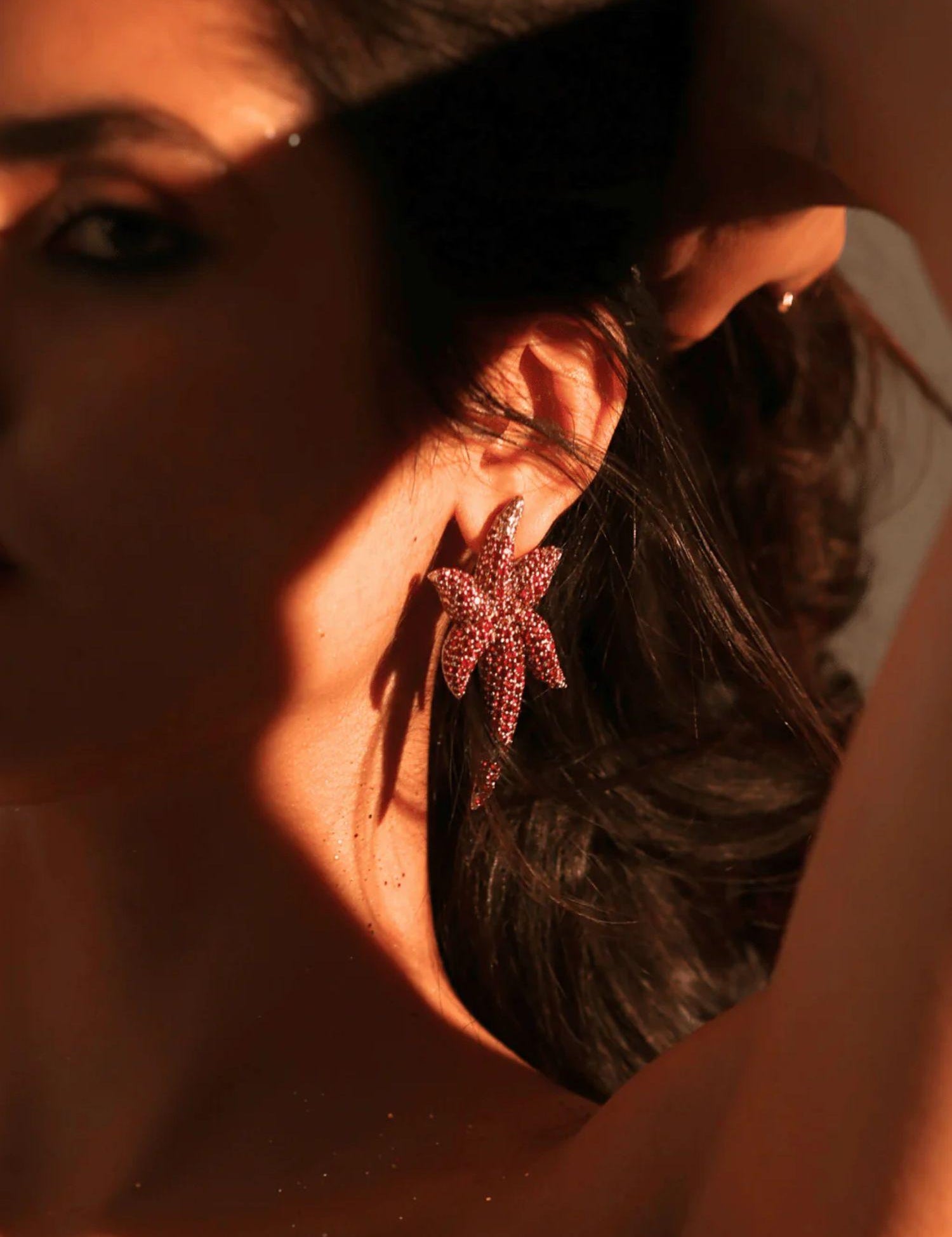 Model wearing sculptural CZ starfish earrings in warm dramatic lighting