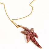 Angled flat lay of gold starfish pendant necklace on a neutral background
