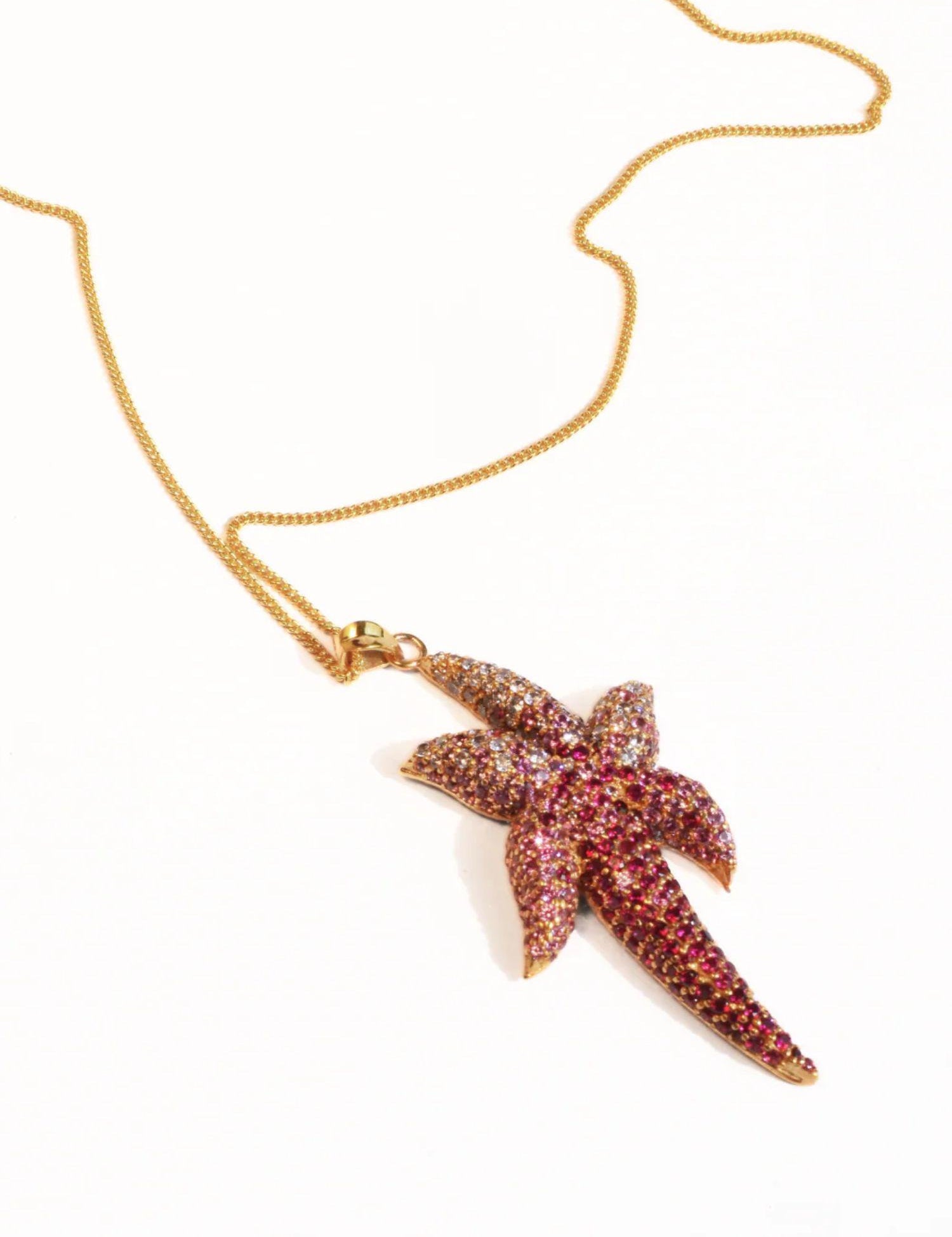 Angled flat lay of gold starfish pendant necklace on a neutral background