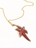 Angled flat lay of gold starfish pendant necklace on a neutral background