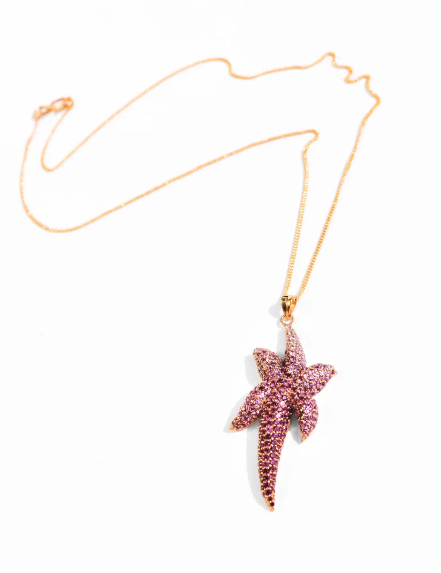 Minimalist product shot of gold starfish pendant necklace on white background