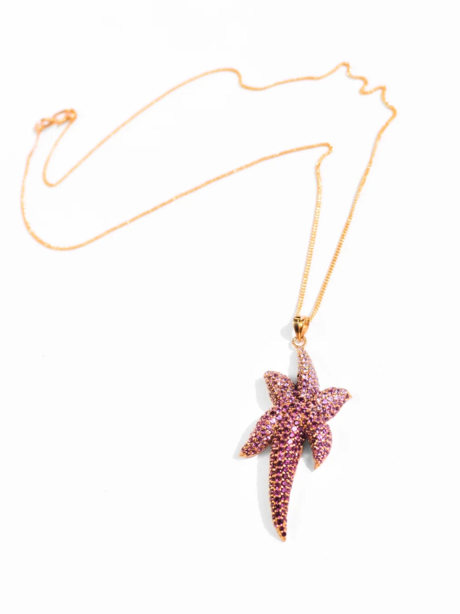 Minimalist product shot of gold starfish pendant necklace on white background