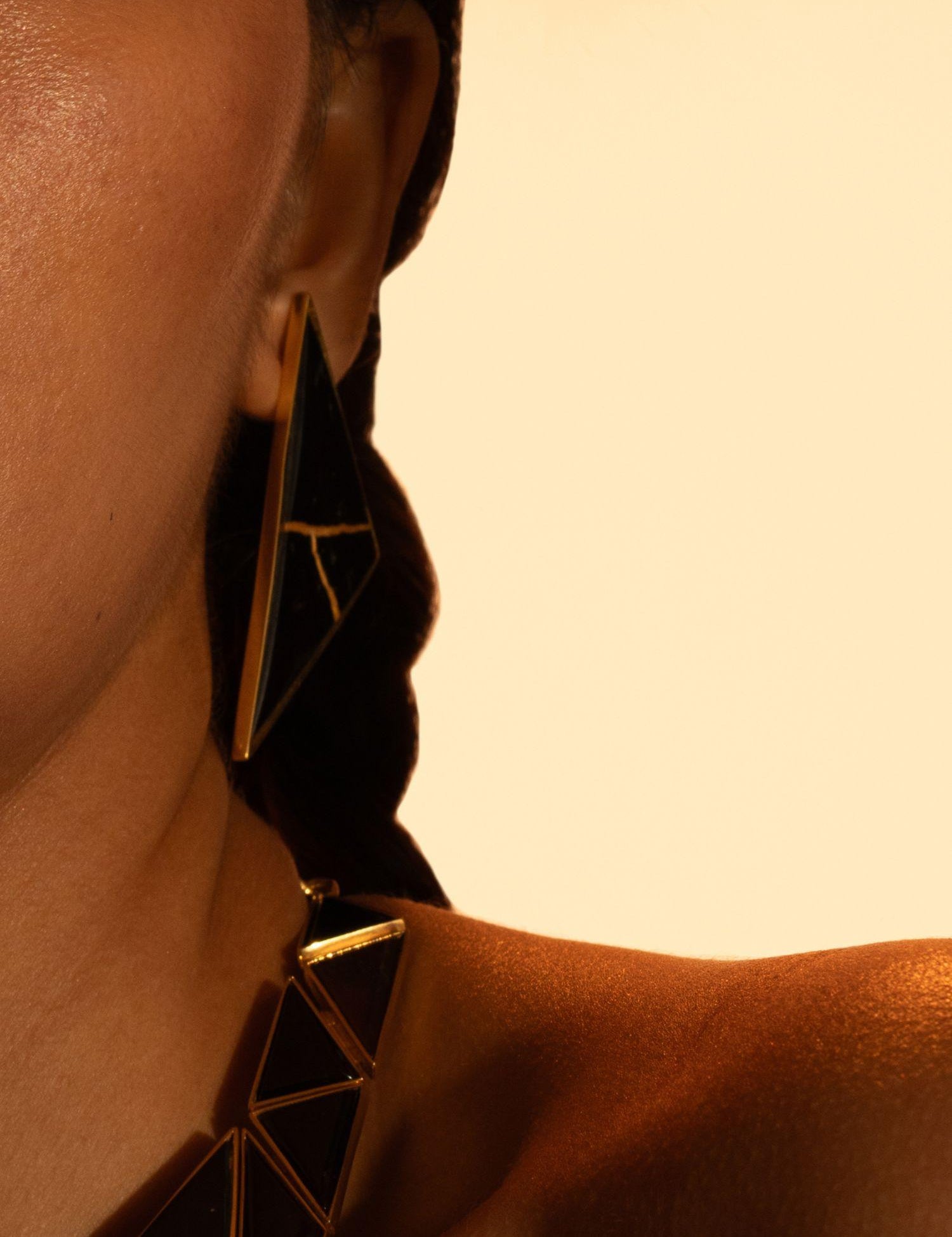 Model wearing full Tsugumi kintsugi set, earrings and necklace together in a warm editorial portrait.