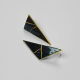 Tsugumi kintsugi triangular drop earrings with black enamel and gold crack detail on neutral background.