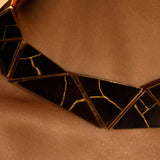 Tsugumi kintsugi statement necklace worn close to décolletage showing gold crack detail on black panels.