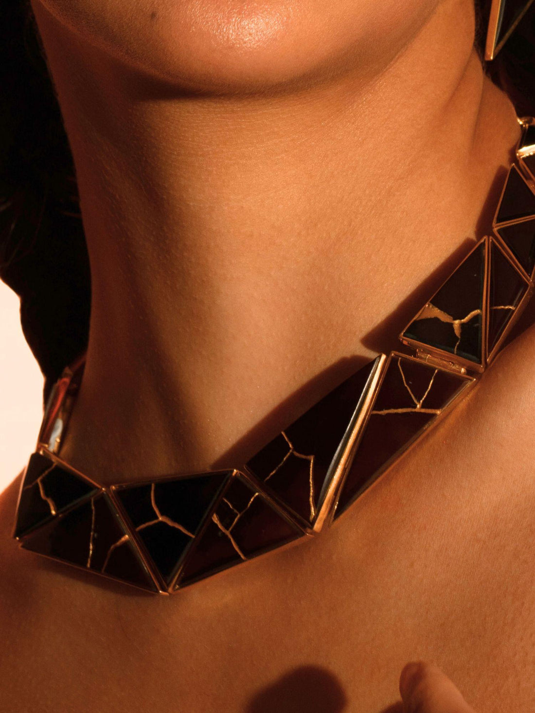 Tsugumi kintsugi necklace with black enamel panels and gold crack detail, full length with chain on neutral background.