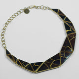 Tsugumi kintsugi necklace with black enamel panels and gold crack detail, full length with chain on neutral background.